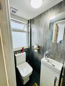 a bathroom with a white toilet and a sink at Enjoy the comfort at private room en-suite with free Parking - near Luton airport in Luton +1 photo