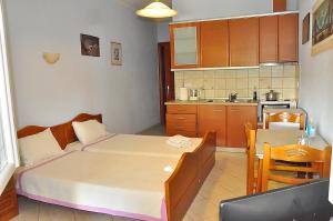 a bedroom with a bed and a table and a kitchen at Studios Kostas & Despina in Lidia