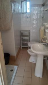 a white bathroom with a sink and a toilet at Casa San Sebastiano in Ficarra