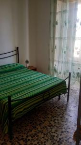a bedroom with a bed with a green striped sheets at Casa San Sebastiano in Ficarra