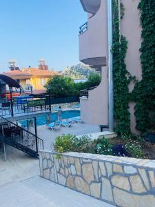 a building with a swimming pool with a stone wall at Sarıgerme Apart otel in Ortaca