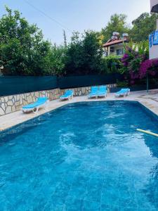 a large swimming pool with blue chairs and a house at Sarıgerme Apart otel in Ortaca