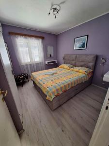 ムルテルにあるApartman Juranの紫の壁のベッドルーム1室(ベッド1台付)