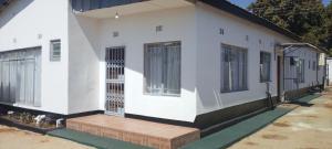 a white house with a wooden porch and windows at LaJoy Lodge in Lusaka
