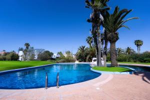 einen Pool mit Palmen neben einem Golfplatz in der Unterkunft Villa in Golf Resort with Shared Pool in Bouznika