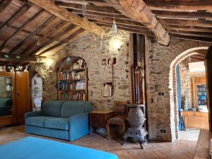 Una sala de estar con un sofá azul y una pared de piedra. en Attic with balcony at Locanda del Capo, en Capannori