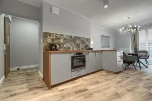 eine Küche mit weißen Schränken und einem Tisch mit Stühlen in der Unterkunft Apartamenty MUNN 3 Szczecin in Stettin