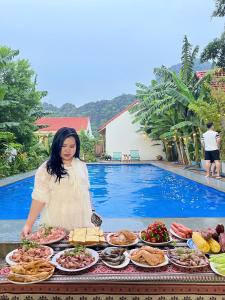 a woman standing next to a buffet of food next to a pool at Hang Mua Green Retreat in Xuân Sơn