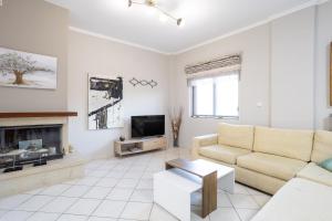 a white living room with a couch and a tv at Sofia's seaview house in Platanias