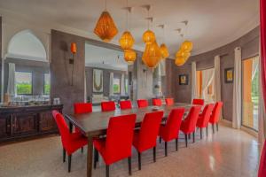 ein Esszimmer mit einem langen Tisch und roten Stühlen in der Unterkunft Villa Chocolat Deluxe in Marrakesch