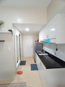a kitchen with white cabinets and a black counter top at Cebu Stay Rental - Sunvida Tower Residences in Cebu City