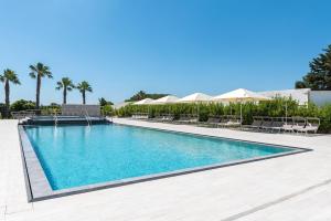 a swimming pool with chairs and umbrellas at a resort at Alfema Rooms in Ugento