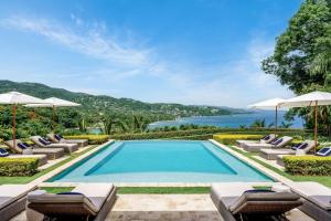 Una imagen de una piscina con tumbonas y sombrillas. en Round Hill Hotel & Villas, en Montego Bay