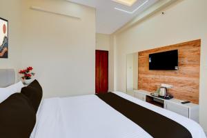 a bedroom with a white bed and a tv on a wall at Hotel O Airport Suites in Muthugadahalli +24 photos