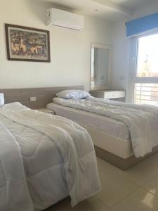 ein Schlafzimmer mit zwei Betten und einem Fenster in der Unterkunft 3 bedroom apartment Marina Residence New Alamein in El-Alamein
