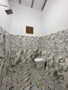 a bathroom with a toilet and a stone wall at The luxy bay in Arugam Bay