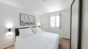 a white bedroom with a large white bed and a window at Villa Bell'Aria Korcula in Vela Luka