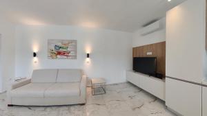 a living room with a white couch and a tv at Villa Bell'Aria Korcula in Vela Luka