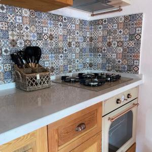 a kitchen with a stove and a tile wall at Gaba Dede Evleri-Bayram Evi in Cumalı