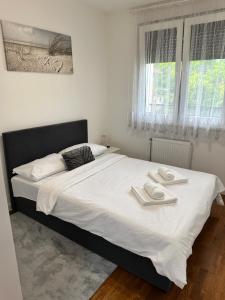 a bedroom with a large white bed with two towels on it at Stan na dan Banja Luka DM in Ivišovo Greblje