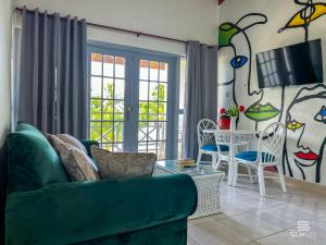 a living room with a green couch and a table at Sunset Lane Apartment Hotel in Saint James