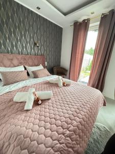 a bedroom with a large pink bed with towels on it at Chill&Love Apartament 