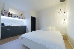a bedroom with a white bed and a kitchen at City Mini Studio in Bratislava