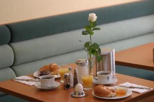 einen Tisch mit Frühstückszutaten und eine Vase mit einer Rose in der Unterkunft Memphis Hotel in Frankfurt am Main