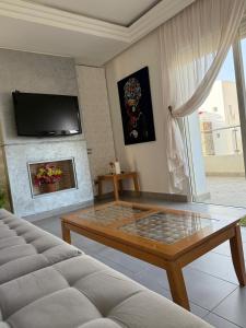 a living room with a coffee table and a fireplace at PERLA SAÏDIA APPART XXL Clima IPTV Piscine Parking Jardin in Saidia  +13 photos