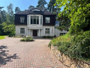 Casa blanca con techo negro y entrada de ladrillo en Villa Lumiere, en Jūrmala