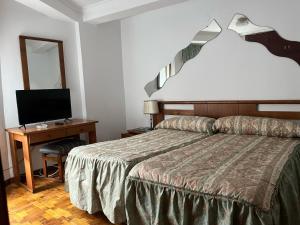 a bedroom with a bed and a desk with a television at Pensión San Francisco in Muñera