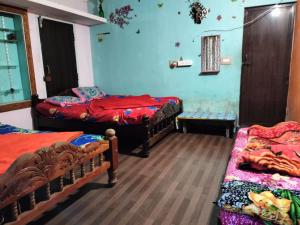 a room with three beds in a room at Laharya couple room in Madikeri