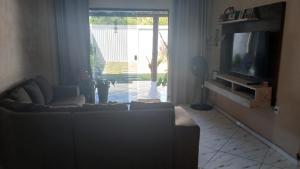 a living room with a couch and a television at Casa Praia Grauçá in Caravelas