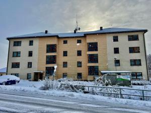 a large building in the snow with a car in front at Apartmán Horálek in Janske Lazne