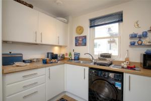 ブリクサムにあるCaptains Rest - 2 bedroom apartment in the heart of Brixhamのキッチン(白いキャビネット、洗濯機付) +20枚の写真