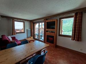 a living room with a wooden table and windows at Résidence Les Airelles - appartement plein sud, parking couvert - 50m des pistes MAE-8394 in Montgenèvre