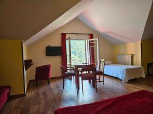a bedroom with a bed and a table and chairs at Valley View Hotel Encumeada in Senhora do Rosário +24 photos
