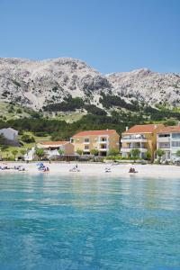 a beach with buildings and people laying on the beach at Apartments Capic in Baška