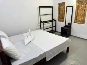 ein Schlafzimmer mit einem Bett mit weißen Laken und einem Spiegel in der Unterkunft TravelLodge Eco in Arugam Bay