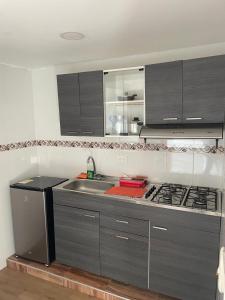 a kitchen with gray cabinets and a sink and a stove at Aparta hotel Montecristo Suites in Quimbaya +9 photos