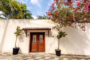 a house with a wooden door and two potted trees at Apartamento Villa Siena Condomínio À Beira Mar próximo ao Aeroporto in Salvador
