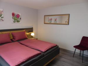a bedroom with a bed with pink sheets and a red chair at Ferienwohnung Jesse in Braunlage