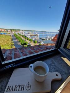 a cup of coffee sitting on a table in front of a window at Ferienwohnung Hafenpanorama Speicherresidenz Barth 4 5 in Barth