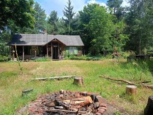 a house in a field with a fire in front of it at Leśna Chata Polesie 