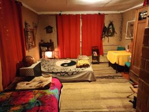 a bedroom with two beds and red curtains and a table at Leśna Chata Polesie 