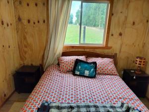 a bedroom with a bed with a pillow on it at Cabañas Los Tatas in Puerto Octay