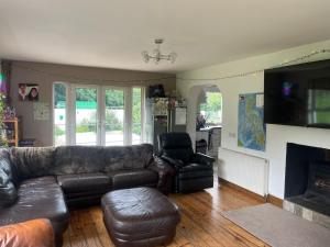 a living room with a leather couch and a fireplace at The Portsalon House in Cloghfin