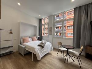 a bedroom with a bed and a table and two windows at Gabika Apartment 1 in Bilbao