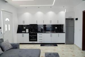 a white kitchen with white cabinets and a couch at Villa Merkaj in Sarandë