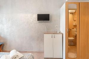 a bathroom with a white cabinet with a tv on the wall at Apartments Jelica in Pag +31 photos